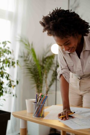 Young African businesswoman drawing blueprint at office desk.
